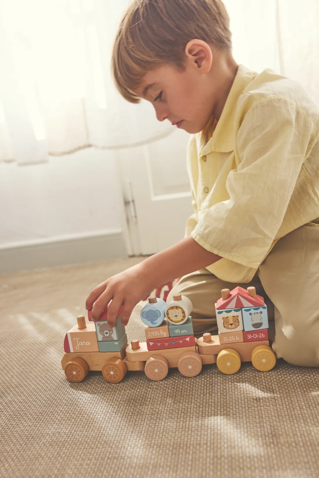 Niño jugando con un tren de madera de la colección Tutete